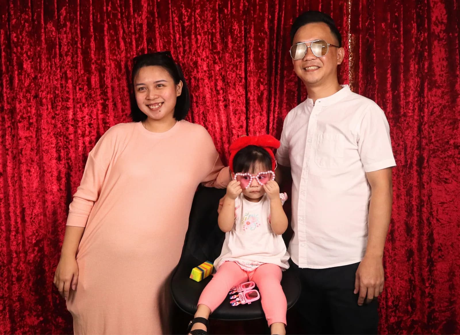 Parents and their daughter wearing playful photo booth glasses