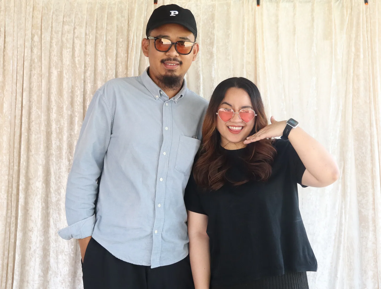 A couple smiling together in heart-shaped photo booth glasses