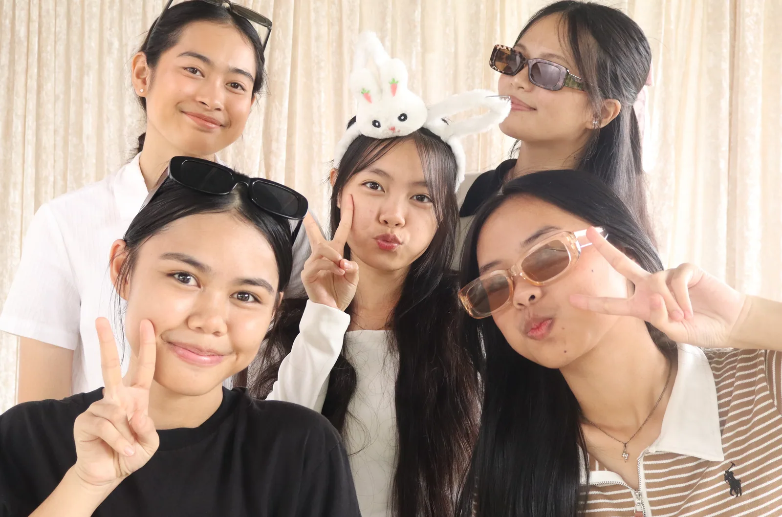 Five friends posing closely together with glasses and bunny ears